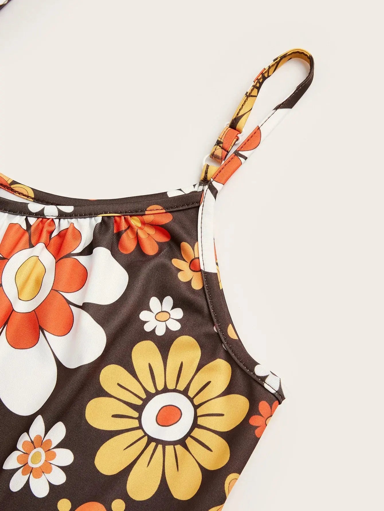Woman wearing a loose floral print jumpsuit with thin straps.